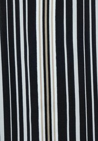 Vertikala svartvita ränder med en central sektion av texturerad beige, svart och vit vävd vertikalrandig tyg.