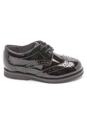 Zwarte lakleren brogue schoen met vetersluiting en decoratieve perforaties, zijaanzicht op een witte achtergrond.