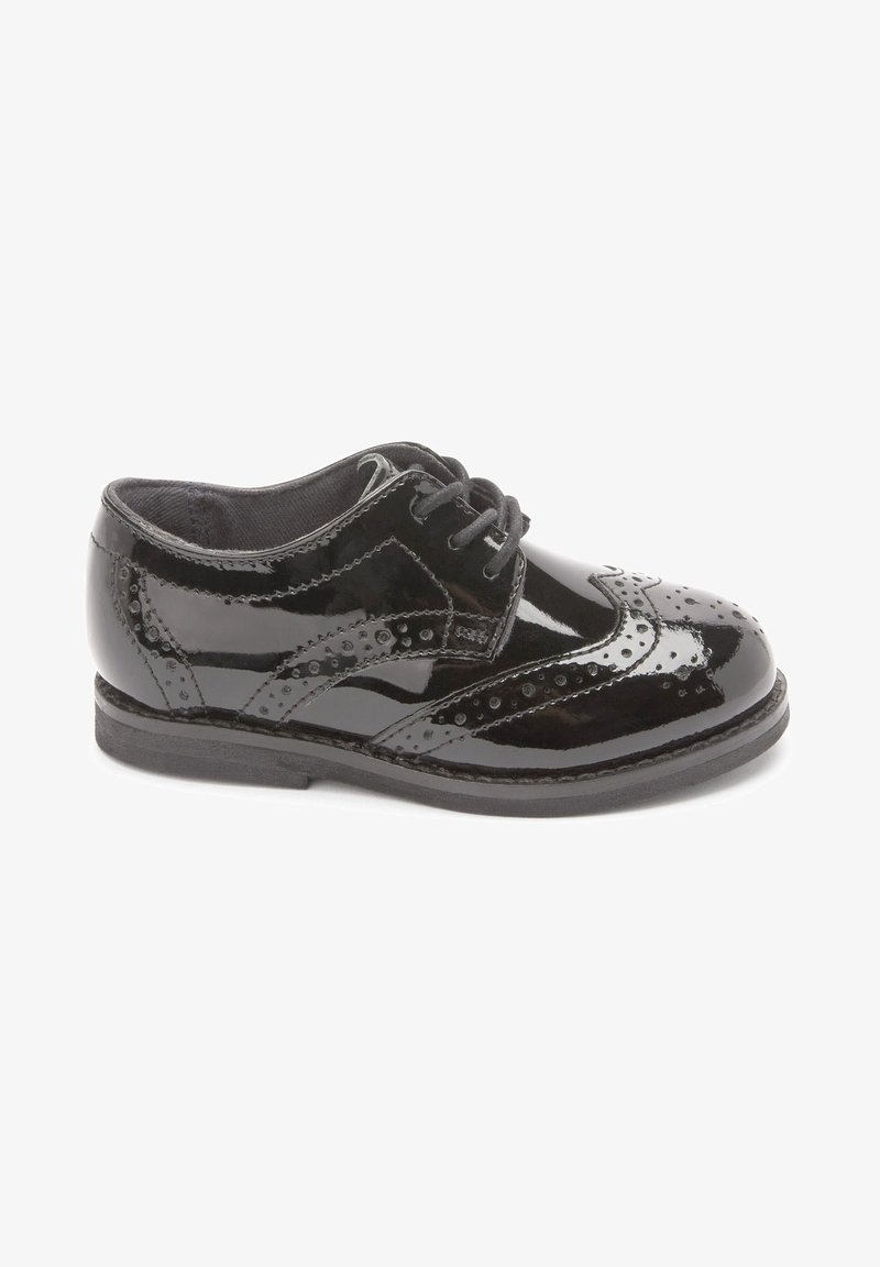 Chaussure brogue en cuir verni noir avec fermeture à lacets et perforations décoratives, vue de côté sur fond blanc.
