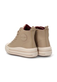 Zapatillas altas de color marrón con parte superior de cuero suave, suela de goma blanca, forro interior rojo y detalle de logo en el lateral. Presenta una costura mínima.
