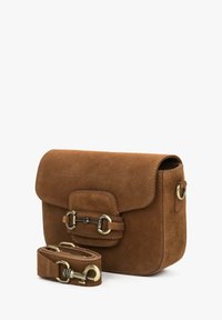 Brązowa torba na ramię z zamszu z klapką, metalowymi pierścieniami i odpinanym paskiem. Miękka faktura i prostokątny kształt.