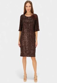 Brązowa sukienka z cekinami, z dekoltem w kształcie litery U i krótkimi rękawami, ozdobiona kwiatowym akcentem na ramieniu oraz dopasowanym fasonem.