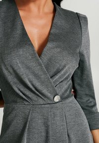 Szara sukienka o kroju kopertowym z głębokim dekoltem w literę V, rękawami o długości trzech czwarte, teksturowanym materiałem oraz wyraźnym srebrnym guzikiem w pasie.