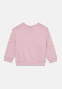 Blød lyserød langærmet sweatshirt med rund hals, ribbede manchetter og kant, lagt fladt på en hvid baggrund.