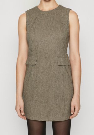 Sleeveless tailored brown herringbone dress with flap pockets at hips, worn with black sheer tights on a standing person.