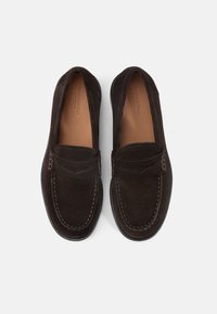 Dark brown suede loafers with stitching details, smooth rounded toe, and a moccasin-style design. Beige interior lining. Rubber sole.