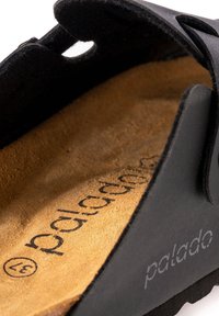 Zwarte sandaal met een gestructureerde band, voorzien van een bruine suède binnenzool. De merknaam "palado" is in de zool geperst, wat grip en ondersteuning garandeert.