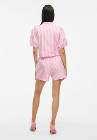 Różowo-biały pasiasty top z krótkim rękawem, z bufkami, oraz dopasowane szorty. Gładka tkanina, luźny krój, elastyczna talia i podkreślone mankiety.