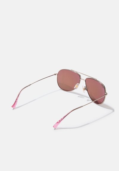 Gafas de sol con un marco metálico, lentes en tono rosa y varillas curvas y transparentes en color rosa. Cuentan con almohadillas nasales ajustables para mayor comodidad.