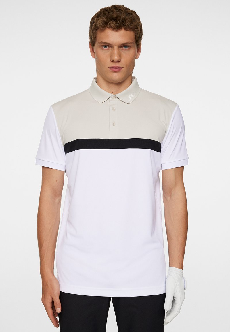 Herrarnas polotröja i vitt, med ljusgrå axlar och ett svart horisontellt rand över bröstet, med en tre-knappsknäppning.