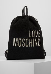 Svart fleece-ryggsäck med snörstängning, prydd med "LOVE MOSCHINO" i metallisk text. Inkluderar svarta läderremmar och guldfärgade detaljer.