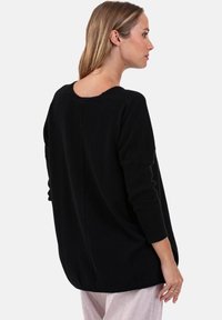 Schwarzer gestrickter Pullover mit Rundhalsausschnitt, langen Ärmeln und lockerem Schnitt. Verfügt über gerippte Bündchen und eine Rückennaht als strukturelles Detail.