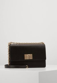 Crna torba od kože s remenom preko tijela u zlatnoj boji, preklopnim zatvaračem i pravokutnim metalnim ukrasom. Teksturirana površina s glatkim završetkom.