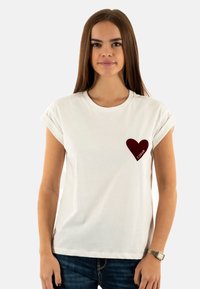 Camiseta de algodón blanca con mangas enrolladas, que presenta un corazón burdeos impreso en el pecho con la palabra "COLOR" debajo.