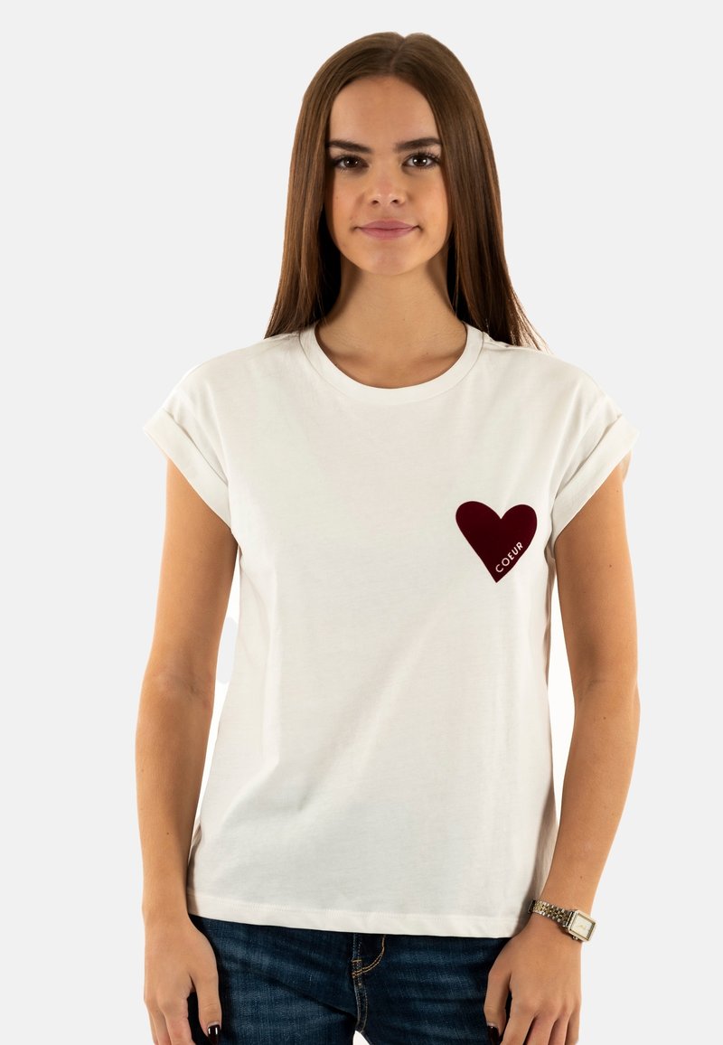 Camiseta de algodón blanca con mangas enrolladas, que presenta un corazón burdeos impreso en el pecho con la palabra "COLOR" debajo.