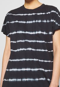 Black t-shirt with tie-dye pattern featuring white horizontal stripes. Made of soft fabric with a standard crew neckline and short sleeves.