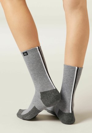 Graue gerippte Socken mit schwarz-weißen Streifen, mit verstärkten grauen Fersen- und Zehenbereichen für zusätzliche Haltbarkeit. Markentag sichtbar.