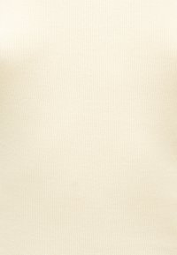 Κοντινή λήψη μπεζ ραβδωτού υφάσματος με λεπτές κάθετες γραμμές και διακριτή υφή.