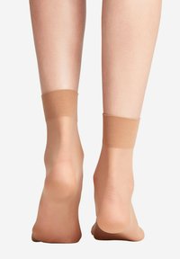 Durchsichtige, hautfarbene Knöchelsocken aus leichtem Material mit einer glatten Textur und einer einheitlichen beigen Farbe, ausgestattet mit einem dezenten elastischen Bund.