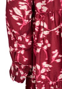Ilgais rankovėmis burgundiško spalvos suknelė, pagaminta iš medvilnės, su rožiniais ir baltais gėlių raštais, mygtukais užsegamomis rankovėmis ir sluoksniuota konstrukcija.