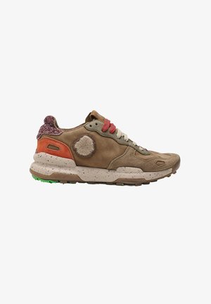 Zapatilla deportiva de ante y tela marrón con suela beige moteada, cordones rojos y blancos, y detalle naranja en el talón, mostrada desde el lado izquierdo.