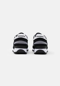 Svart-hvite Saucony-sneakers med mesh- og semsket skinnmaterialer, polstret krage og en teksturert gummisåle. Logo vist på hælen.