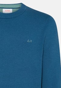 Maglione blu lavorato a maglia con colletto a girocollo a coste. Presenta un piccolo logo ricamato in verde chiaro sul petto. Texture morbida e design informale.