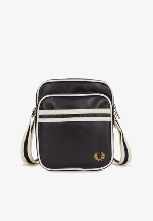 Sac bandoulière noir avec rayures blanches, sangle réglable, poche avant zippée et petit logo en forme de couronne de laurier dorée en bas à droite.