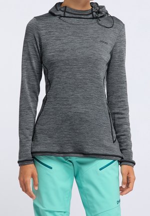 Dopasowana ciemnoszara bluza z kapturem i długim rękawem ze sznurkiem, w połączeniu z jasnoniebieskimi spodniami z zamykanymi na zamek kieszeniami, pokazana na stojącej osobie.