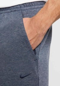 Joggers de color azul marino hechos de un material suave y texturizado. Cuenta con un bolsillo lateral y un detalle de logo oscuro en la cadera. Corte casual.
