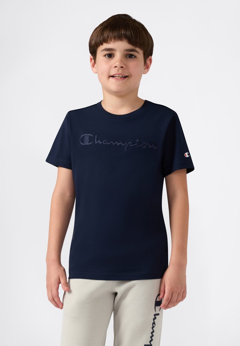 T-shirt di cotone blu navy a maniche corte, che presenta un logo "Champion" ricamato con un punto di colore contrastante sul petto.