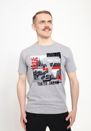 Camiseta de algodón gris con un estampado gráfico con acentos en negro y rojo, que representa paisajes urbanos de Tokio y un texto que dice "TOKIO JAPÓN".
