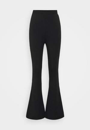 Czarne spódnice typu flare wykonane z elastycznego materiału. Projekt charakteryzuje się wysokim stanem i zwężającym się końcem, który otwiera się poniżej kolana.