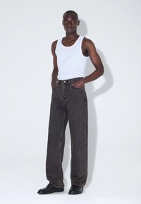 Schwarze Jeans mit hoher Taille und geradem Bein, ausgestattet mit vier Taschen, Knopf- und Reißverschluss sowie kontrastierenden Steppnähten.