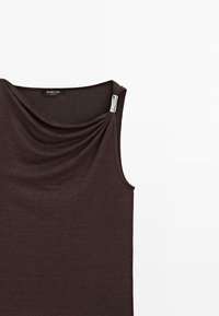 Haut sans manches marron foncé avec un col drapé et une boucle décorative argentée près de l'épaule droite.