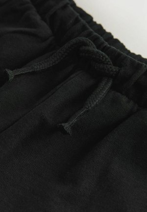 Juodi šortai su raišteliu, pasižymintys lygiu, minkštu audiniu. Turi pintą raištelį ir tamprų juosmenį bei šonines kišenes.