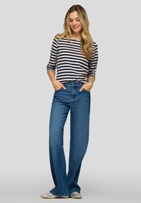 Striped long-sleeve top in cream and navy, paired with flared blue jeans. The jeans feature a high waist and wide leg design.
