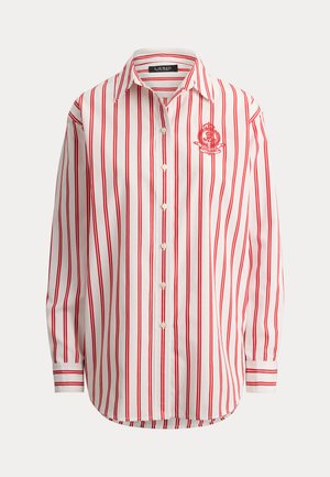 Λευκό πουκάμισο με κατακόρυφες κόκκινες ρίγες, μακριά μανίκια, μυτερό γιακά και κεντημένο κόκκινο έμβλημα στο αριστερό στήθος.