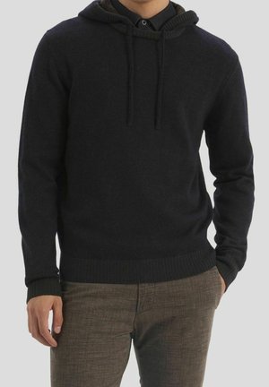 Haut à capuche gris foncé en tissu tricot doux, avec un cordon de serrage, des poignets côtelés et une coupe décontractée, associé à un pantalon marron texturé.