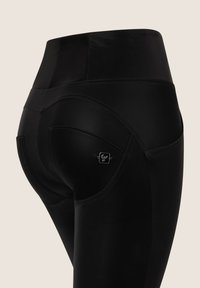 Sorte høyt liv leggings med en glatt, elastisk tekstur. Har buede sømmer og en liten logo detalj på baklommen.