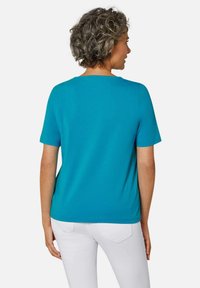 Türkises T-Shirt mit kurzen Ärmeln und rundem Halsausschnitt, aus weichem Material, mit lockerem Schnitt und minimalistischer Gestaltung.