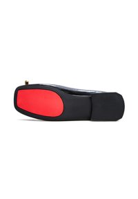 Suela de zapato negra con un acento de goma roja en el centro. Textura suave con forma redondeada y un pequeño detalle de metal dorado en la punta.