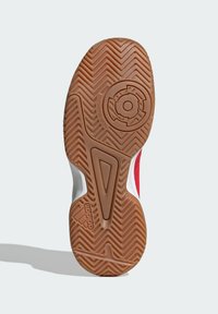 Semelle en caoutchouc avec un motif en chevrons, présentant un design anti-traces. Les accents incluent des éléments rouges et blancs sur les côtés supérieurs.