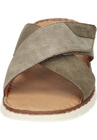 Groene suède sandaal met kruislings straps, leren inlegzool en witte rubberen zool. Kenmerkt zich door een gestructureerde stof en contrasterende stiksels.