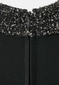 Cuello de prenda negra con tela texturizada y con lentejuelas en la parte superior; incluye un cierre de cremallera y un patrón de punto suave debajo.