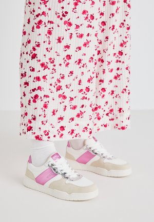 Adidași albi și roz cu un accent din suede gri, având un șiret lucios și un panou lateral roz, asortați cu o fustă lungă plisemată cu imprimeu floral.