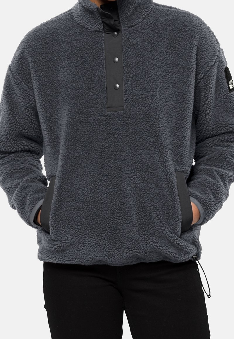 Sudadera de forro polar gris con un cuello alto, tapeta de botones a presión y bolsillos laterales. Presenta un tejido texturado y acentos en negro.