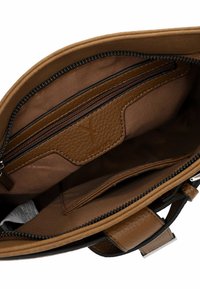 Interno di una borsa a mano in pelle marrone con una fodera in tessuto morbido, dotato di tasche con zip e uno slot per schede. Texture liscia e spazio organizzato.