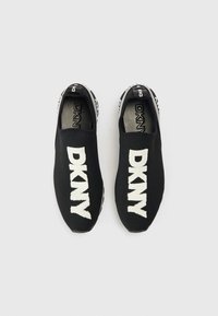 Μαύρα παπούτσια slip-on με πλεκτό επάνω μέρος. Διαθέτουν λευκό λογότυπο "DKNY" στο μπροστινό μέρος. Λαστιχένια σόλα με υφή και μαύρες και λευκές λεπτομέρειες.