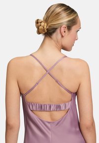 Tylny widok lawendowej sukienki z satyny z krzyżującymi się ramiączkami, z falbaniastym wycięciem. Gładka tekstura i delikatny design.